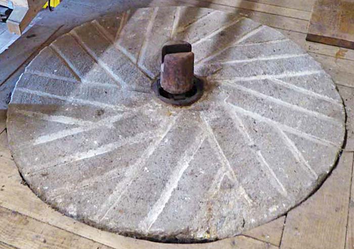 A Millstone Grit millstone set up as a bedstone for grinding flour in Acorn Bank Watermill, Cumbria, UK.
