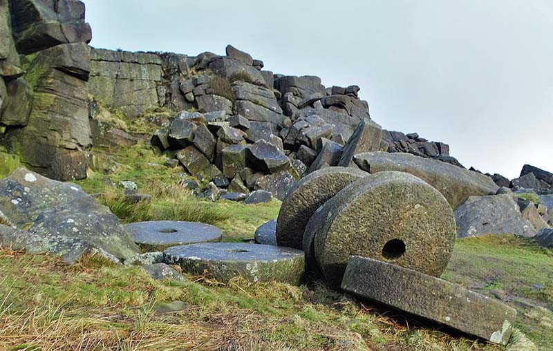 Huge, finished grindstones of Millstone Grit lie abandoned at their quarry site at Stanage Edge, Derbyshire, UK.